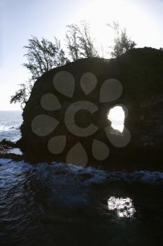 Rock with hole in it in Pacific ocean off island of Maui, Hawaii.