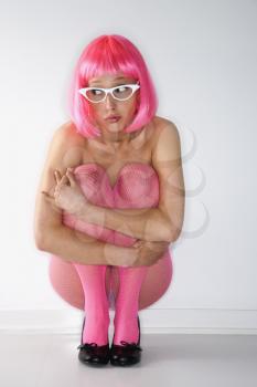 Royalty Free Photo of a Woman in a Pink Wig Kneeling Hugging Herself