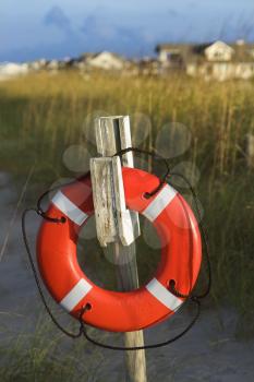 Royalty Free Photo of a Life Preserver Hanging on a Post on a Beach