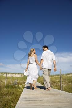 Royalty Free Photo of a Couple Holding Hands Walking Down the Beach Access Path