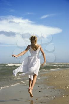 Royalty Free Photo of a Girl Running Down the Beach in a Flowing White Dress