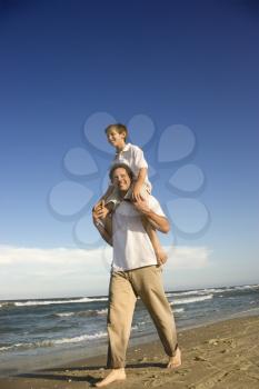 Royalty Free Photo of a Father With a Preteen on His Shoulders on a Beach