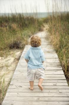 Royalty Free Photo of a Male Toddler Walking on a Beach Access Walkway Toward a Beach