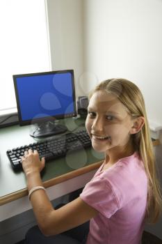 Royalty Free Photo of a Preteen Girl at a Computer Smiling