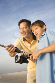 Royalty Free Photo of a Man Shore Fishing on a Beach With a Preteen Boy
