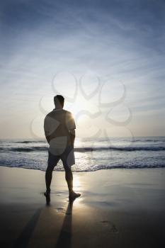 Royalty Free Photo of a Man Standing on a Beach at Sunrise