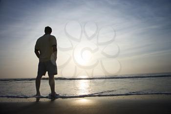 Royalty Free Photo of a Man Standing on a Beach at Sunrise