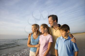 Royalty Free Photo of a Portrait of a Family of Four Posing on the Beach Looking at the Ocean