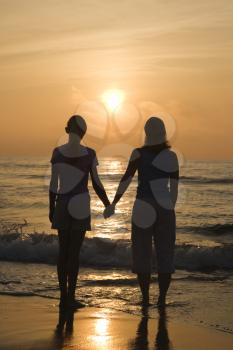 Royalty Free Photo of a Mother and Teenage Daughter Standing on the Beach at Sunset Holding Hands