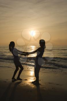 Royalty Free Photo of a Mother and Daughter Holding Gands Spinning on a Beach at Sunset