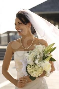 Royalty Free Photo of a Bride Holding a Flower Bouquet and Smiling
