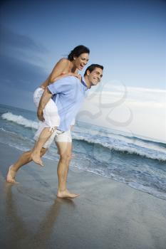 Royalty Free Photo of a Man Giving a Woman a Piggyback on the Beach