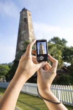 Royalty Free Photo of a Woman's Holding a Digital Camera and Photographing a Lighthouse at Bald Head Island, North Carolina