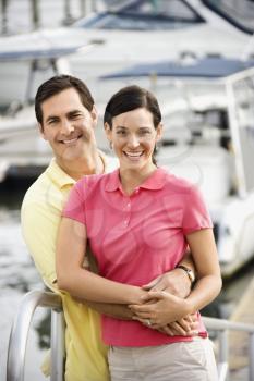 Portrait of Caucasian mid-adult couple embracing at harbor. 