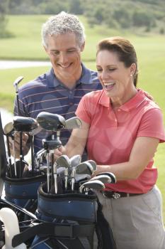 Caucasion mid-adult man and woman smiling and picking out golf club.