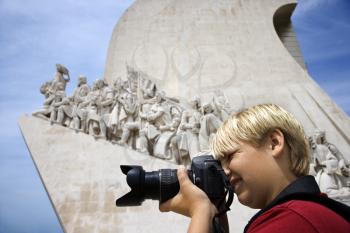 Royalty Free Photo of a Boy Looking Through a Camera at the Monument to the Discoveries in Lisbon, Portugal