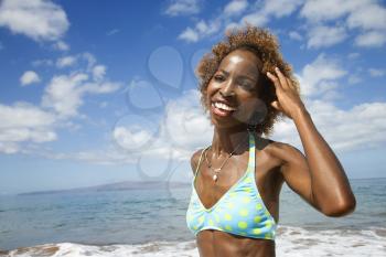 Royalty Free Photo of a Female Smiling and Touching Her Hair With Ocean in the Background