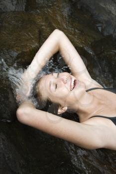 Royalty Free Photo of a Woman Laying in Freshwater Stream Laughing With Arms Over Her Head