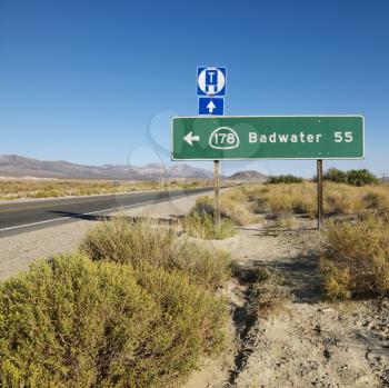 Royalty Free Photo of a Road Sign on the Side of a Desert Road With Direction to Badwater, Death Valley