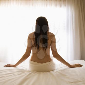 Royalty Free Photo of a Woman Sitting on a Bed