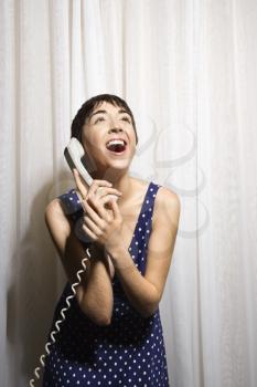 Royalty Free Photo of a Pretty Young Woman Holding a Telephone Receiver to Her Ear and Laughing