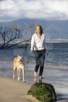 Royalty Free Photo of a Woman Walking a Dog on a Beach in Hawaii