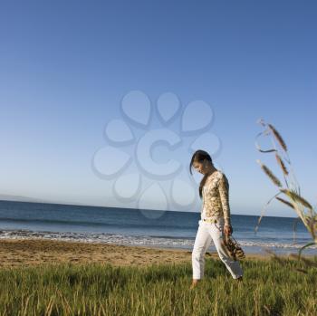 Royalty Free Photo of a Woman Walking on a Beach Carrying Her Sandals