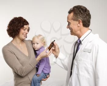 Royalty Free Photo of a Doctor Handing a Mother Medication in a Bottle