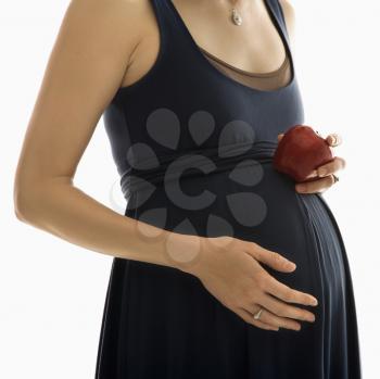 Royalty Free Photo of a Pregnant Woman With Hands on her Belly Holding an Apple
