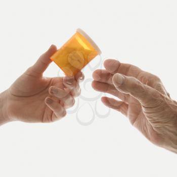 Royalty Free Photo of a Close-Up of a Caucasian Female's Hand Handing a Medication Mottle to an Elderly Caucasian Male Hand