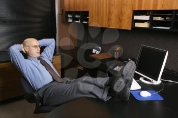 Royalty Free Photo of a Middle-Aged Businessman in an Office Sitting With His Feet on a Desk