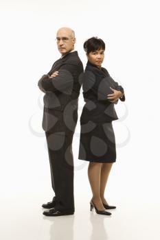 Royalty Free Photo of a Businessman and Businesswoman Standing Back to Back With Arms Crossed Looking Serious