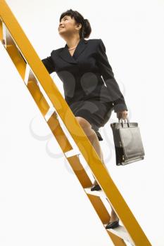 Royalty Free Photo of a Filipino Middle-aged Businesswoman Climbing a Ladder Carrying a Briefcase