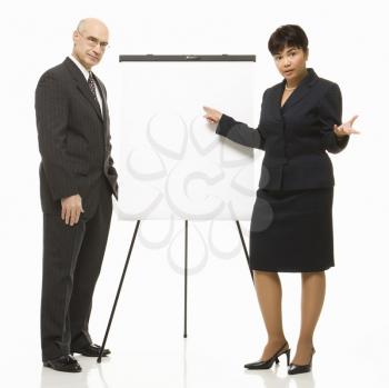 Caucasian middle-aged businessman and Filipino businesswoman standing making presentation against white background.
