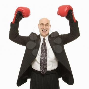 Royalty Free Photo of a Smiling Businessman Standing With Arms Raised Wearing Boxing Gloves