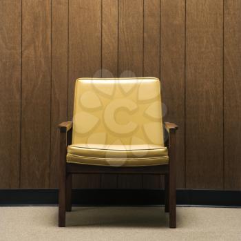 Royalty Free Photo of a Retro Chair Against Wood Paneling in an Office