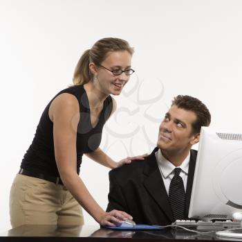 Royalty Free Photo of a Woman Touching a Man's Shoulder and Using Mouse at a Computer