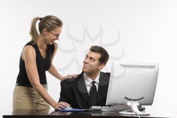 Royalty Free Photo of a Woman Touching a Man's Shoulder and Using Mouse at a Computer