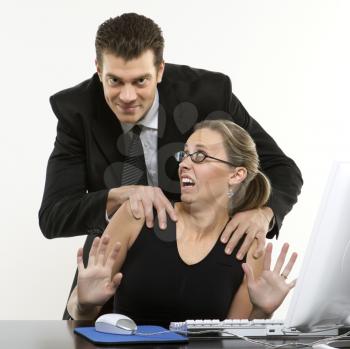 Royalty Free Photo of a Man Sexually Harassing a Woman in an Office