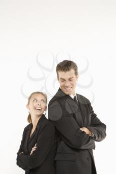 Royalty Free Photo of a businessman and woman standing back to back and smiling at each other. 