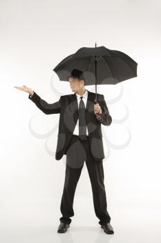 Royalty Free Photo of a Businessman Wearing a Fedora and Holding an Umbrella With Arm Outstretched