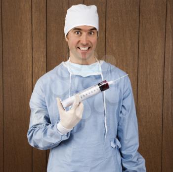 Royalty Free Photo of a Male Surgeon Holding an Over-Sized Syringe and Smiling Maniacally