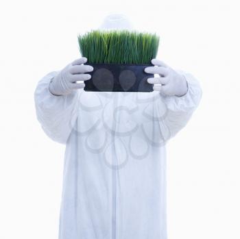 Royalty Free Photo of a Man in Biohazard Suit Holding a Pot of Grass