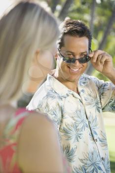 Royalty Free Photo of a Man Tilting Sunglasses at a Woman