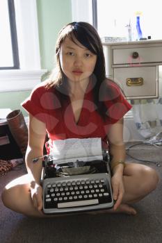 Royalty Free Photo of a Pretty Woman Sitting on the Floor in Holding a Typewriter