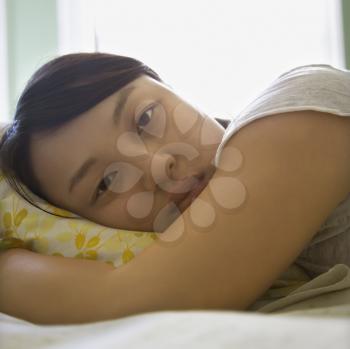 Royalty Free Photo of a Asian Woman Lying in Bed with Head on Pillow 