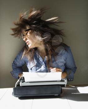Royalty Free Photo of a Woman Sitting at a Typewriter Swinging Her Hair