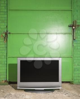 Royalty Free Photo of a Flat Panel Television in Front of a Green Metal Door