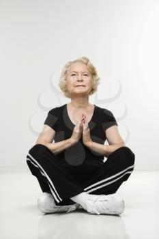 Royalty Free Photo of a Senior Woman Sitting in a Yoga Position on the Floor Meditating