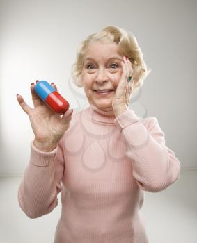 Royalty Free Photo of an Older Woman Holding an Over-sized Pill